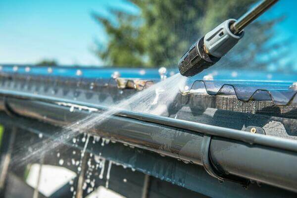 A professional cleaning debris from a home's gutters